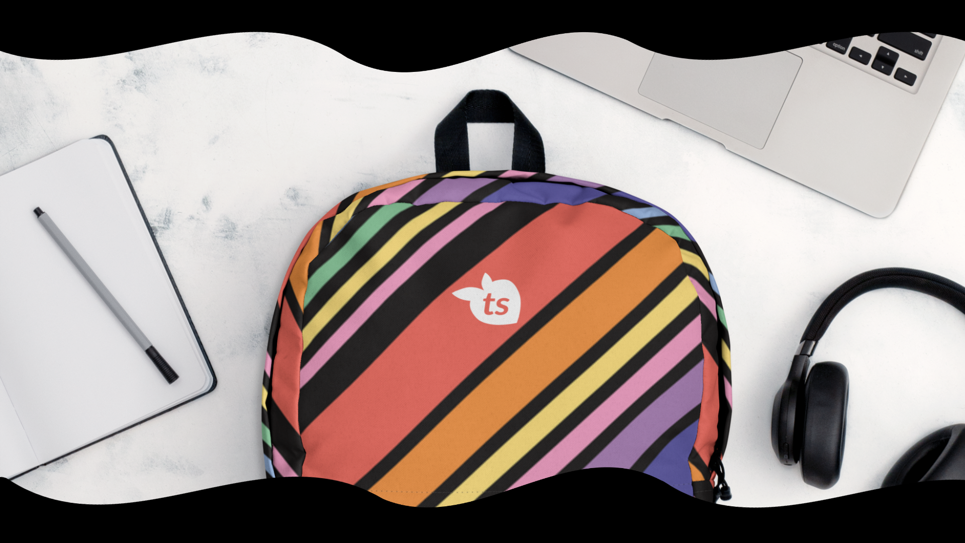 Colorful striped backpack with a logo on a white surface with a laptop, pen, and headphones.